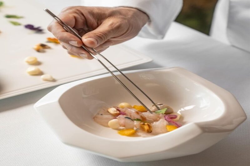 Mano de un chef preparando plato de comida peruana /Andina