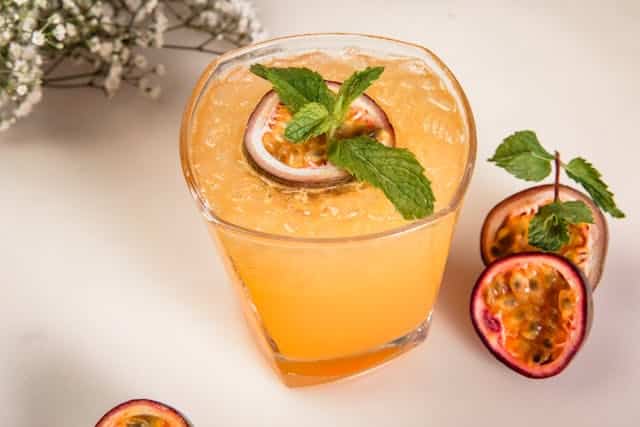 Bebida de Maracuyá servida en un vaso y maracuyá abierto por la mitad / Denys Gromov
