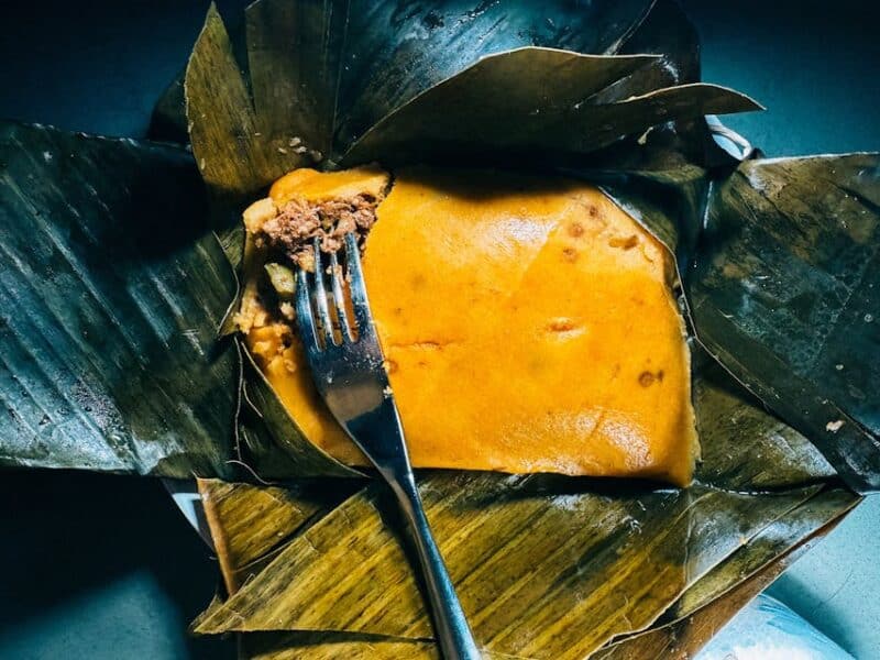 Hallaca sobre hoja de plátano, cortada con un tenedor